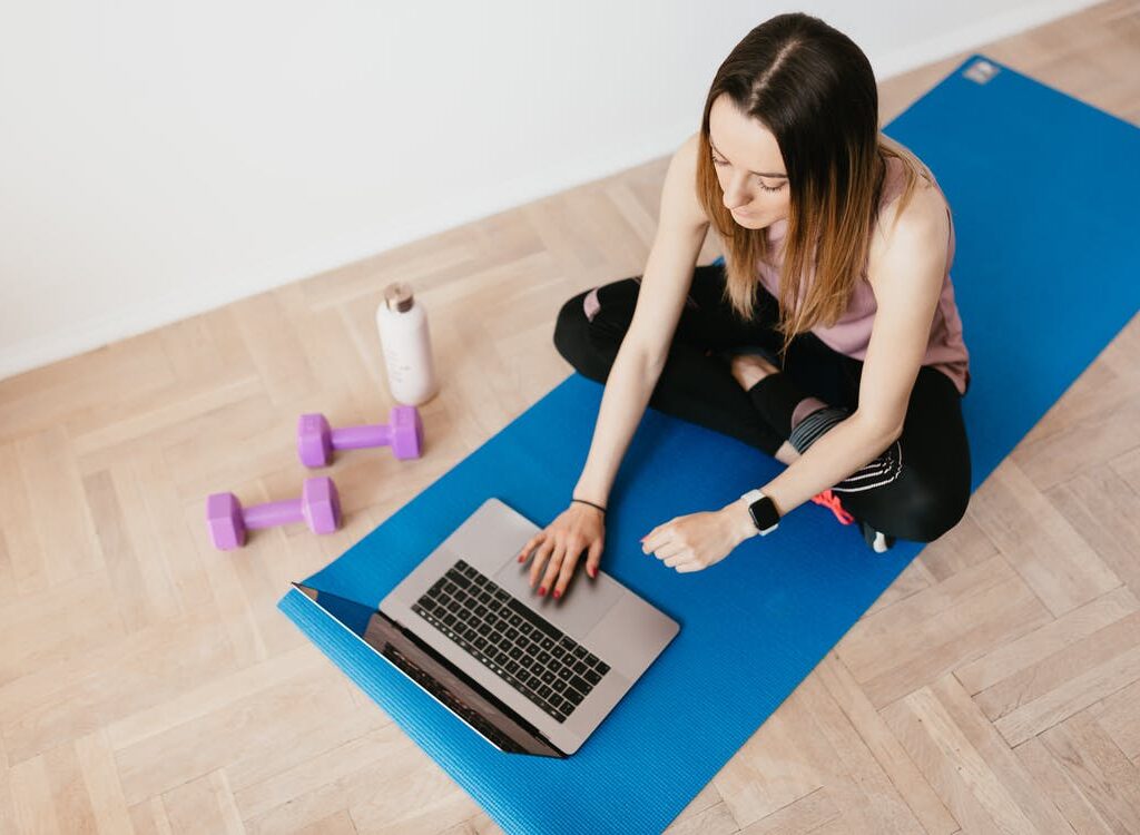 Kvinde med computer på yogamåtte